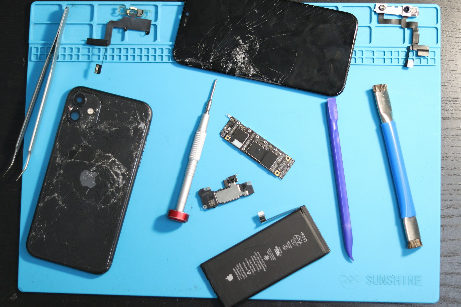 Phone parts scattered on a repair mat.